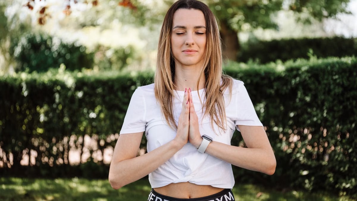 A serene moment of a woman practicing yoga with namaste pose outdoors, embracing mindfulness.