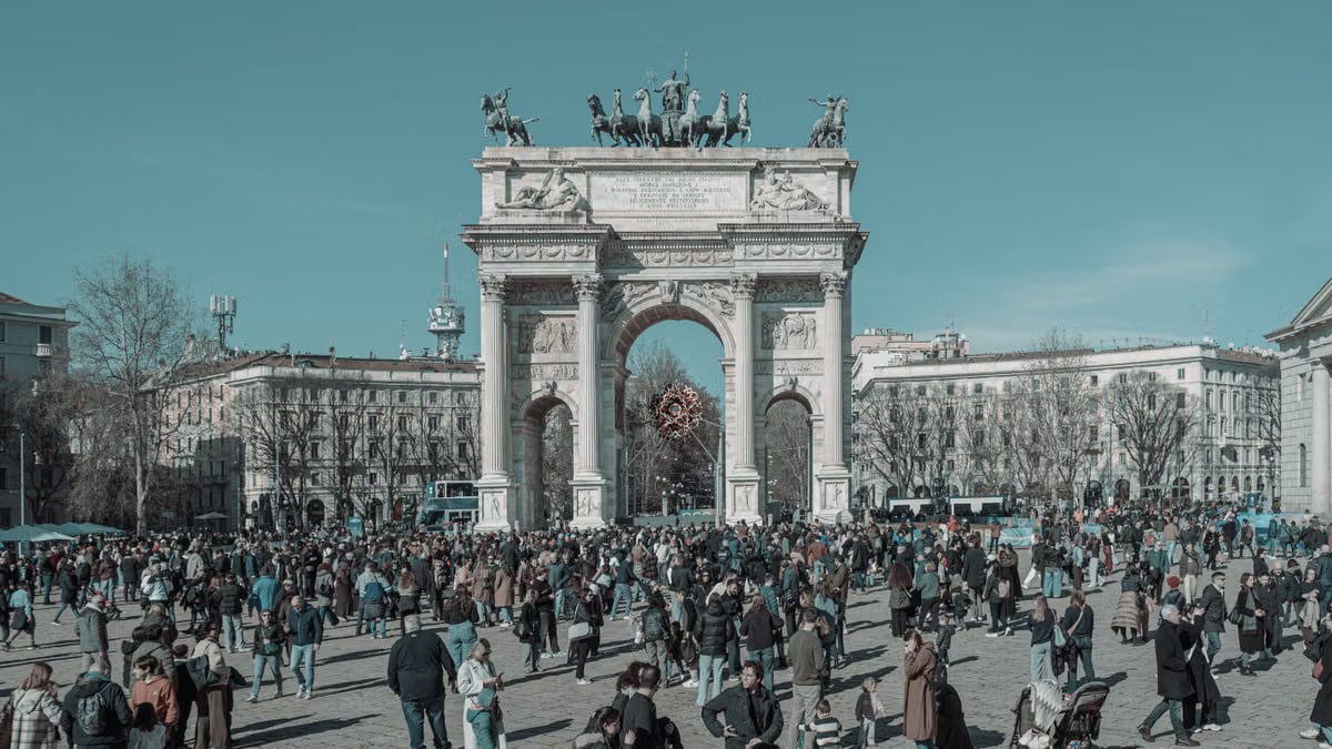 A bustling scene at Arco della Pace in Milan, capturing diverse people under a clear sky.